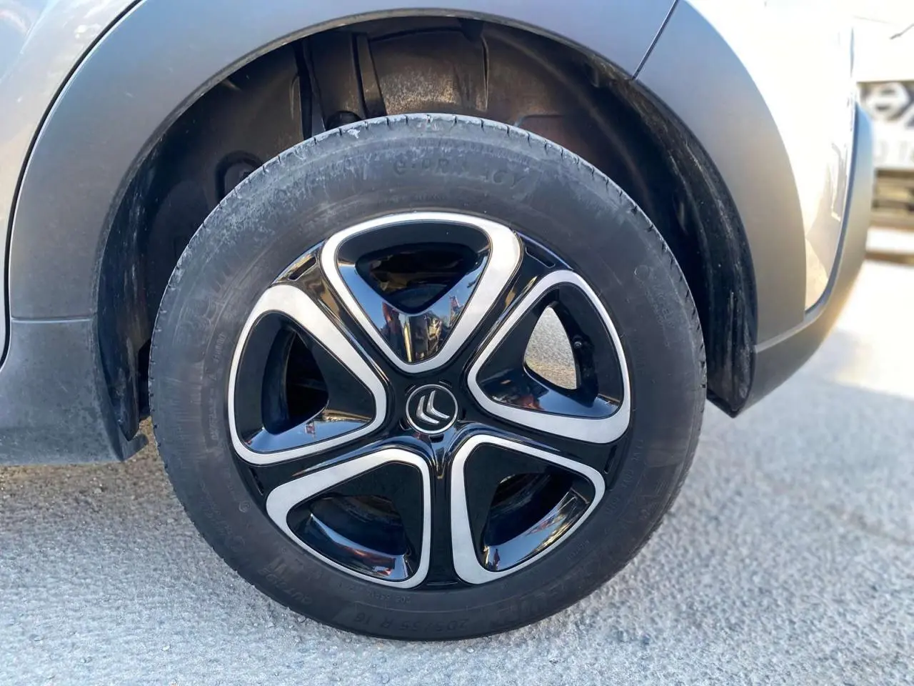 Gros plan sur la roue avant gauche d'une Citroën C3 gris Artense avec jante noire et argentée au design moderne.