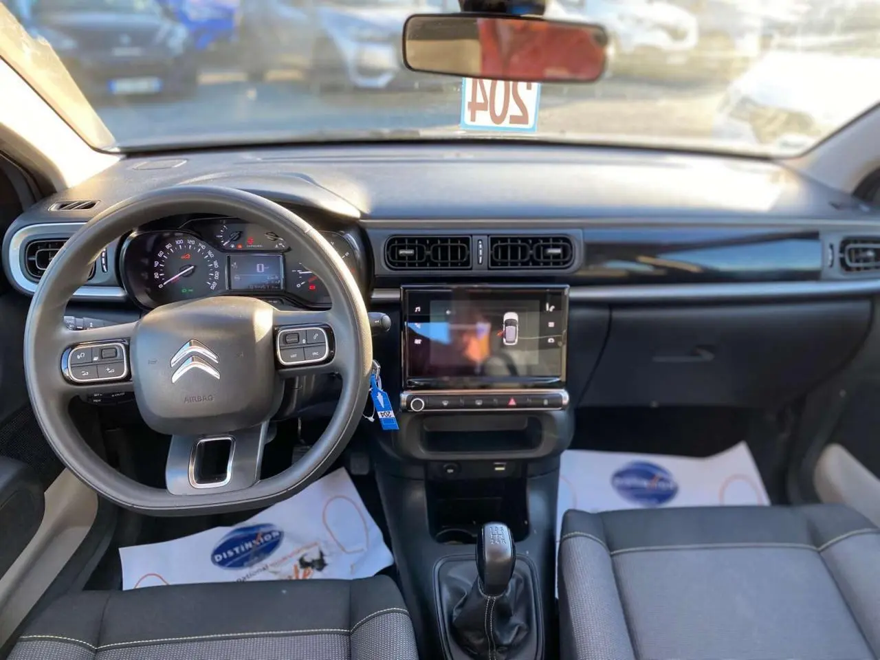 Vue intérieure avant du tableau de bord et volant de la Citroën C3 gris Artense 2022 avec écran tactile et boîte manuelle.