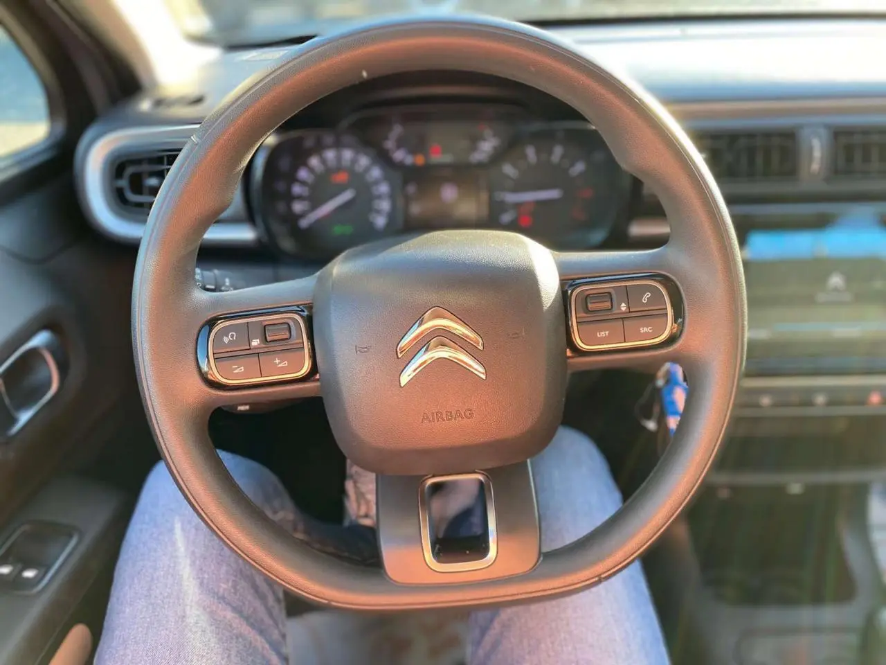 Vue centrée sur le volant de la Citroën C3 2022, avec commandes intégrées et tableau de bord flou en arrière-plan.
