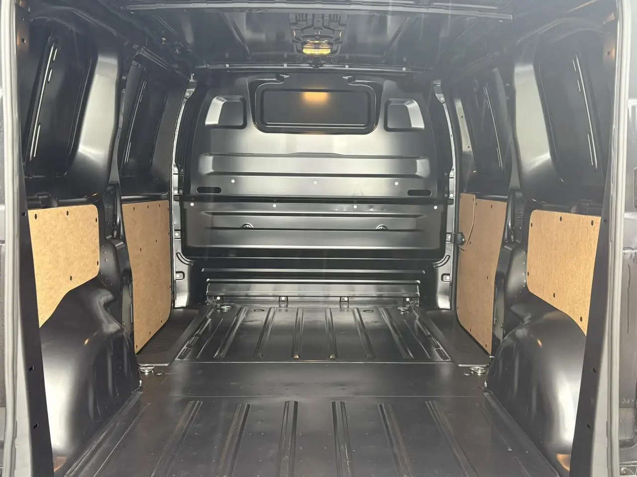 Vue intérieure arrière du Citroën Jumpy gris Titane, montrant l'espace de chargement métallique avec panneaux latéraux en bois clair.