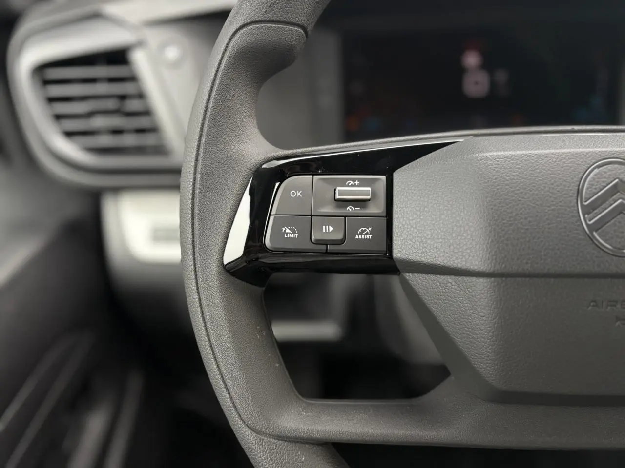 Gros plan sur les commandes au volant noir mat du Citroën Jumpy gris Titane, version 2025, avec logo central visible.