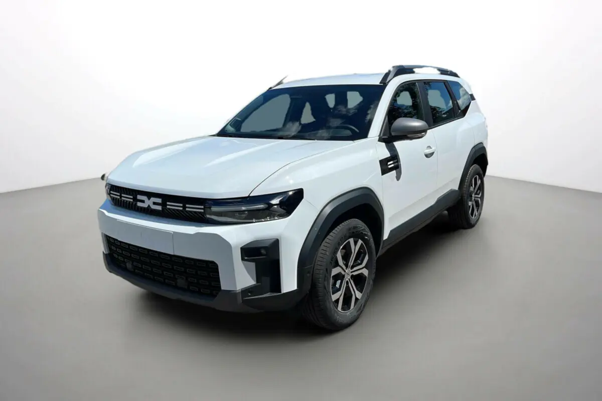 SUV Dacia Bigster blanc glacier en 3/4 avant droit avec barres de toit et jantes alu 17 pouces.