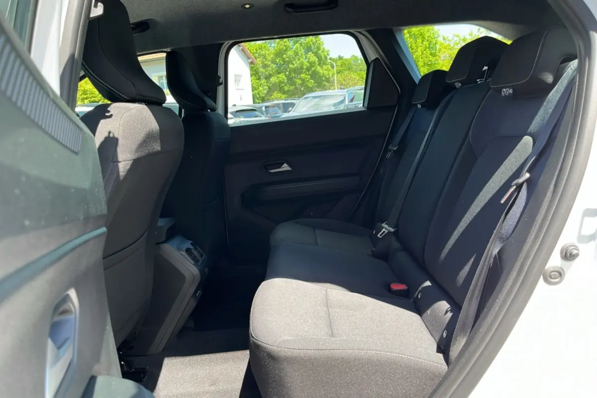 Vue latérale côté droit sur la banquette arrière noire du Dacia Bigster blanc glacier 2025, intérieur spacieux et lumineux.