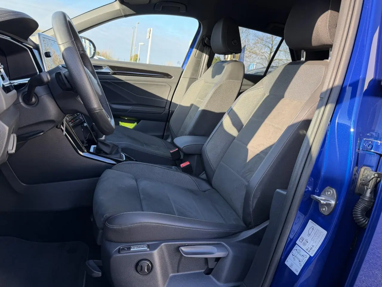 Vue intérieure côté conducteur du Volkswagen T-Roc Bleu Lapiz 2025, montrant les sièges avant et le volant sport R-Line.