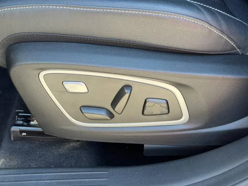 Gros plan sur les commandes de réglage électrique du siège avant côté gauche du Renault Austral gris Schiste 2024.