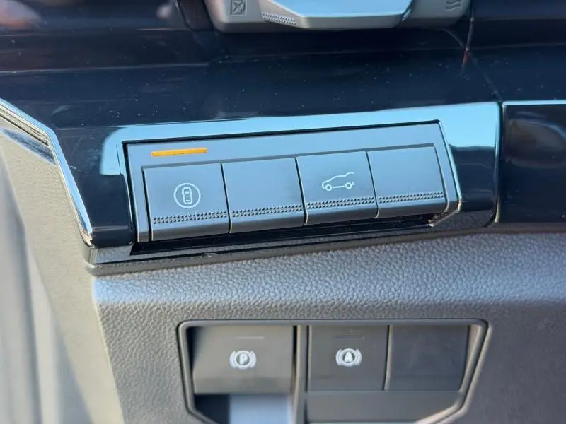 Gros plan sur les boutons de commande noirs brillants du tableau de bord du Renault Austral gris Schiste 2024.