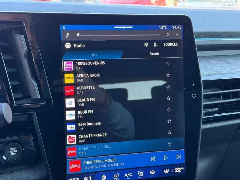 Gros plan sur l'écran tactile central du Renault Austral gris Schiste, affichant les stations radio numériques.