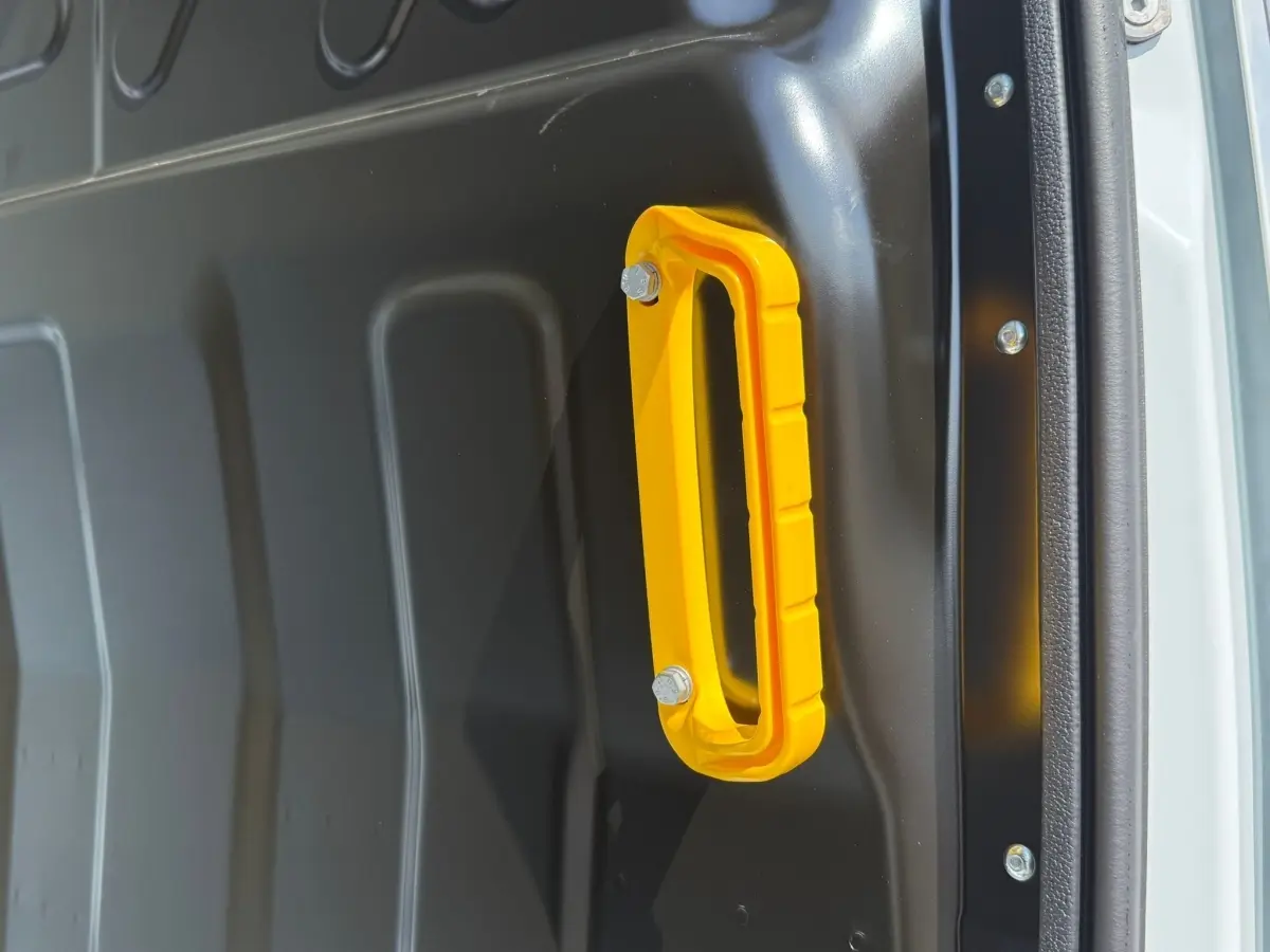 Gros plan sur la poignée jaune fixée à la paroi intérieure grise du véhicule utilitaire Iveco Daily blanc.