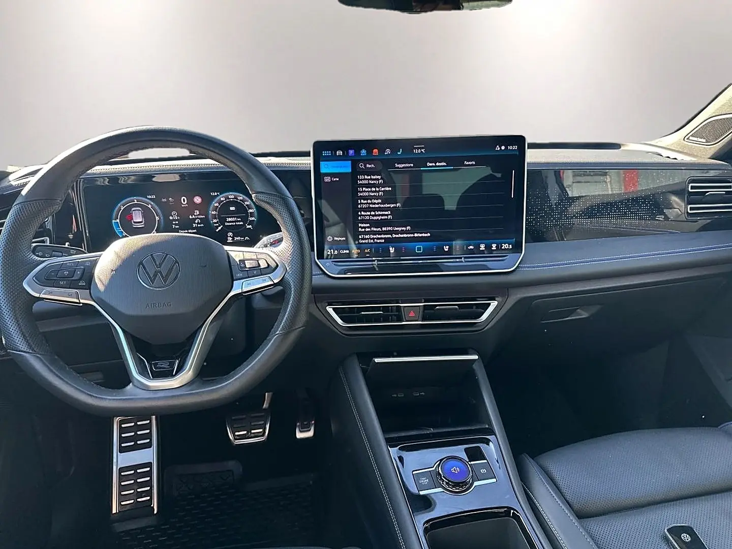 Vue intérieure avant du Volkswagen Tiguan 2024, tableau de bord noir avec écran tactile et volant multifonction cuir.