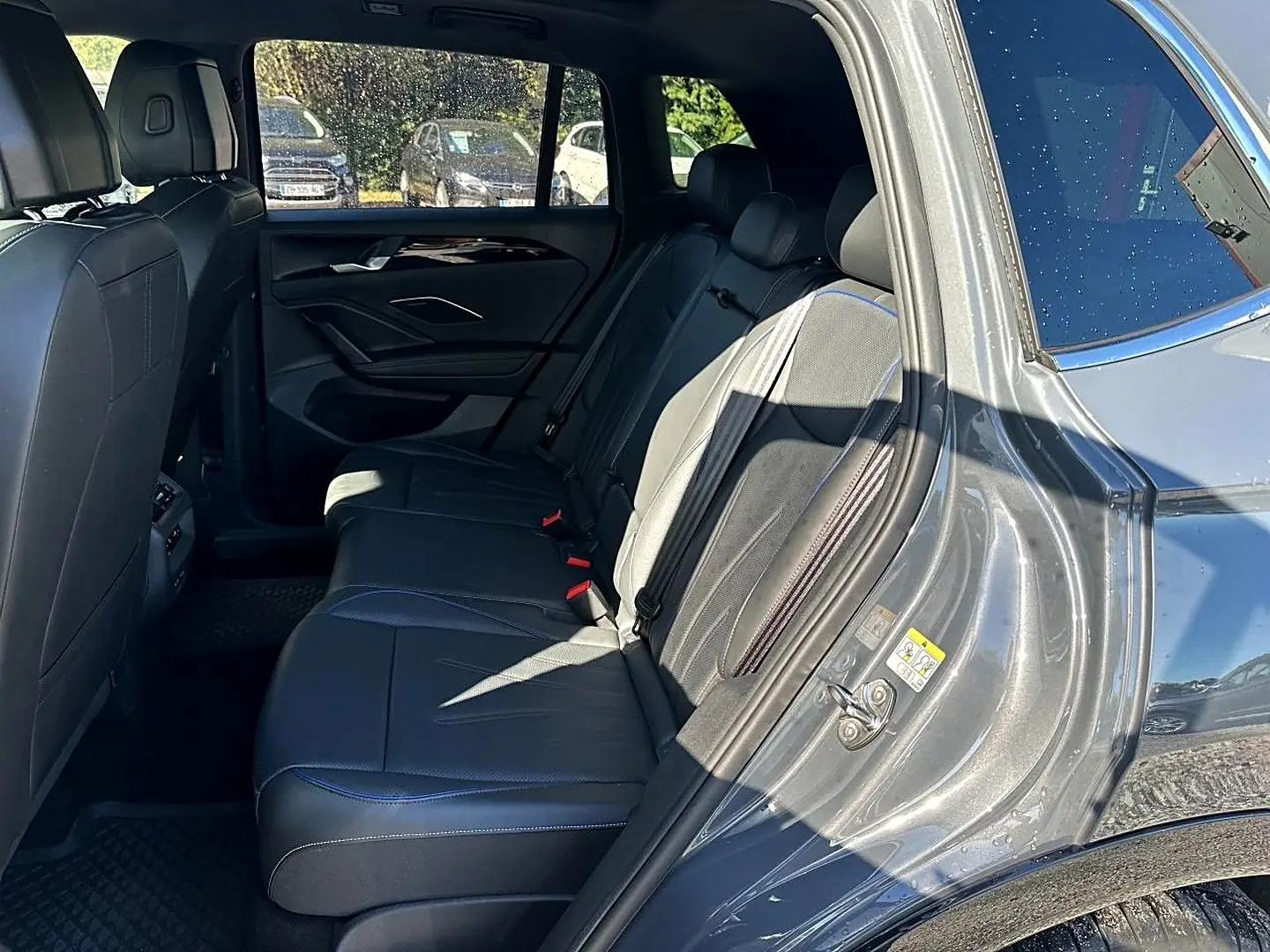 Vue intérieure côté droit des sièges arrière en cuir noir avec surpiqûres bleues du Volkswagen Tiguan gris dauphin 2024.