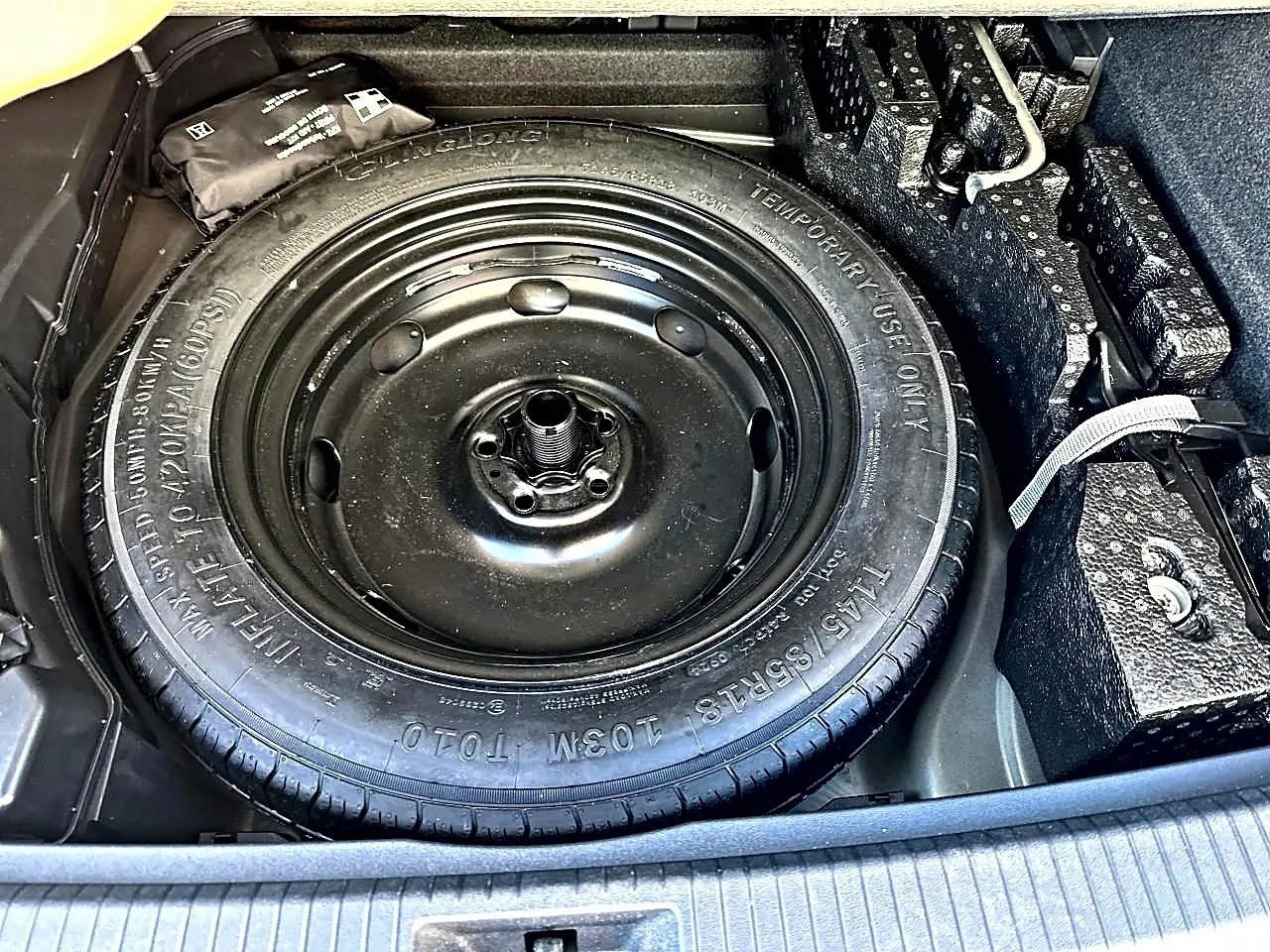 Vue rapprochée de la roue de secours noire dans le coffre du Volkswagen Tiguan gris dauphin 2024.
