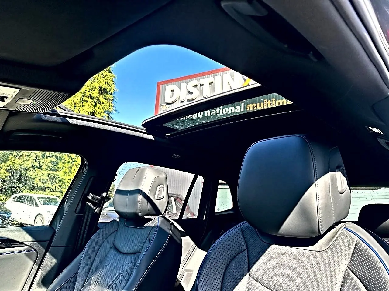 Vue intérieure du Volkswagen Tiguan 2024 gris dauphin, sièges cuir noir R-Line et toit ouvrant panoramique ouvert.