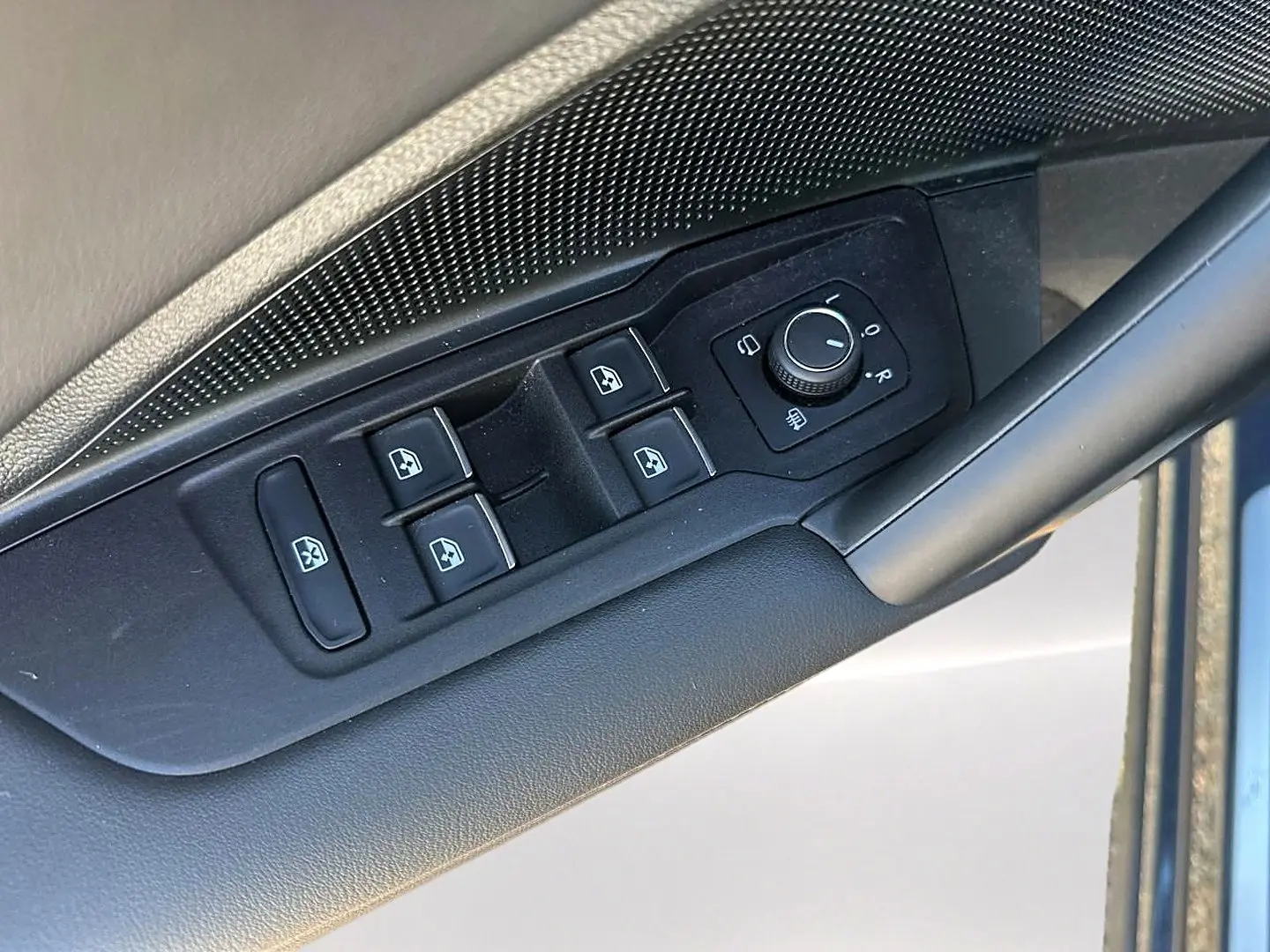Vue rapprochée des commandes de lève-vitres et rétroviseurs côté conducteur du Volkswagen Tiguan gris dauphin 2024.