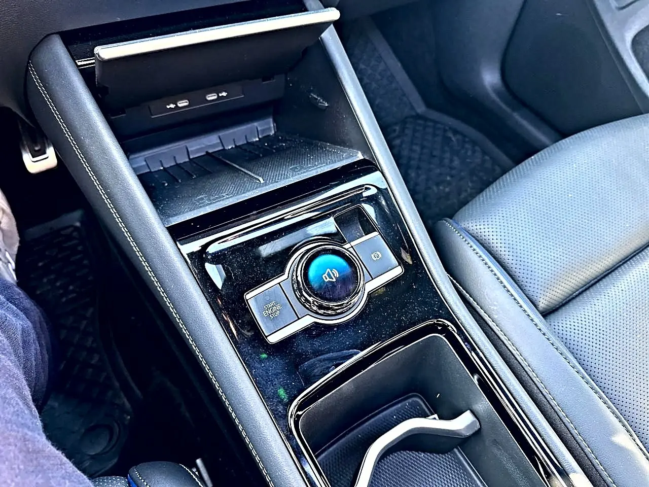 Vue rapprochée de la console centrale noire brillante du Volkswagen Tiguan 2024 avec accoudoir et siège cuir gris.