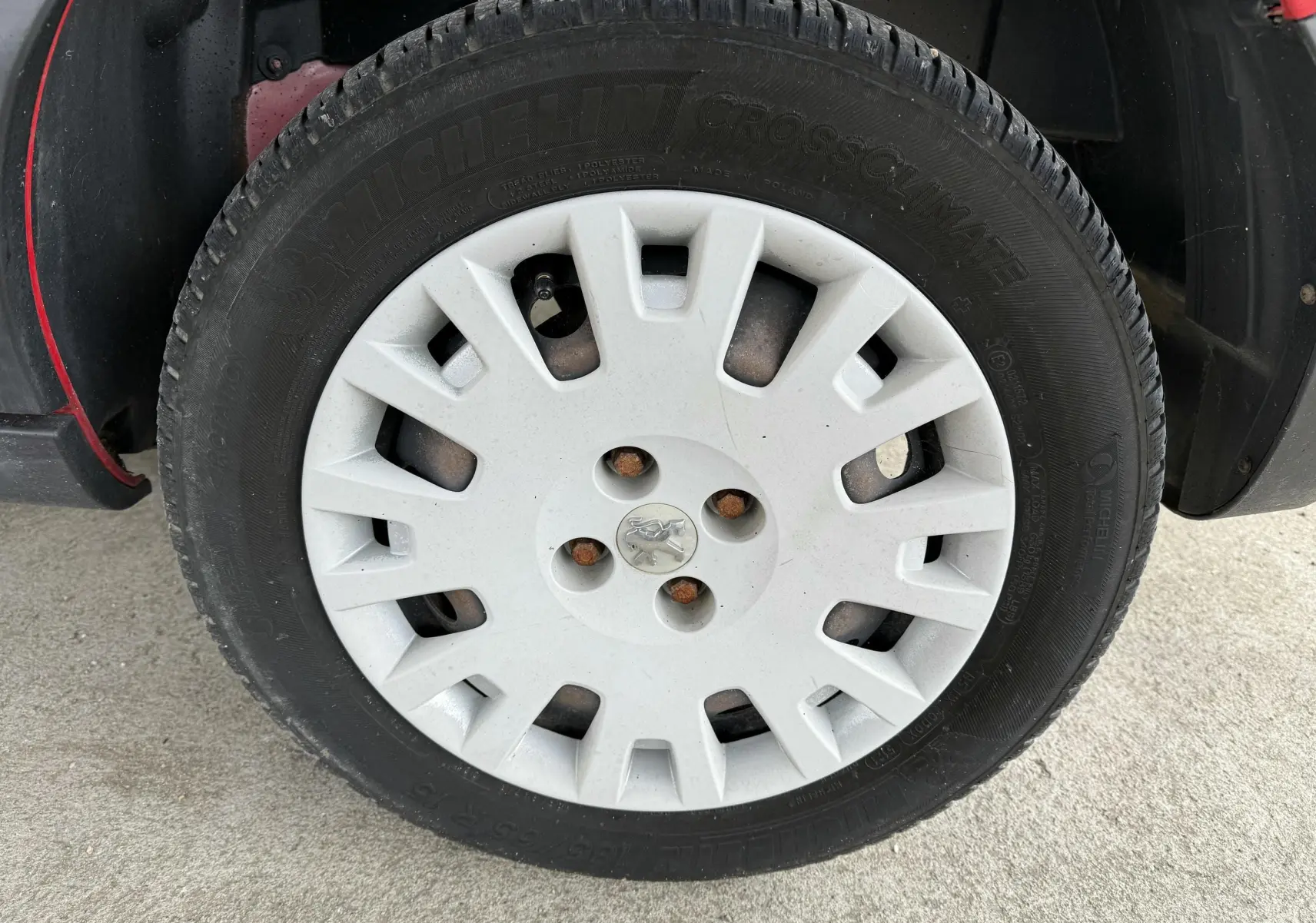 Gros plan sur la roue avant gauche d’un Peugeot Bipper Tepee rouge avec enjoliveur blanc et logo Peugeot central.