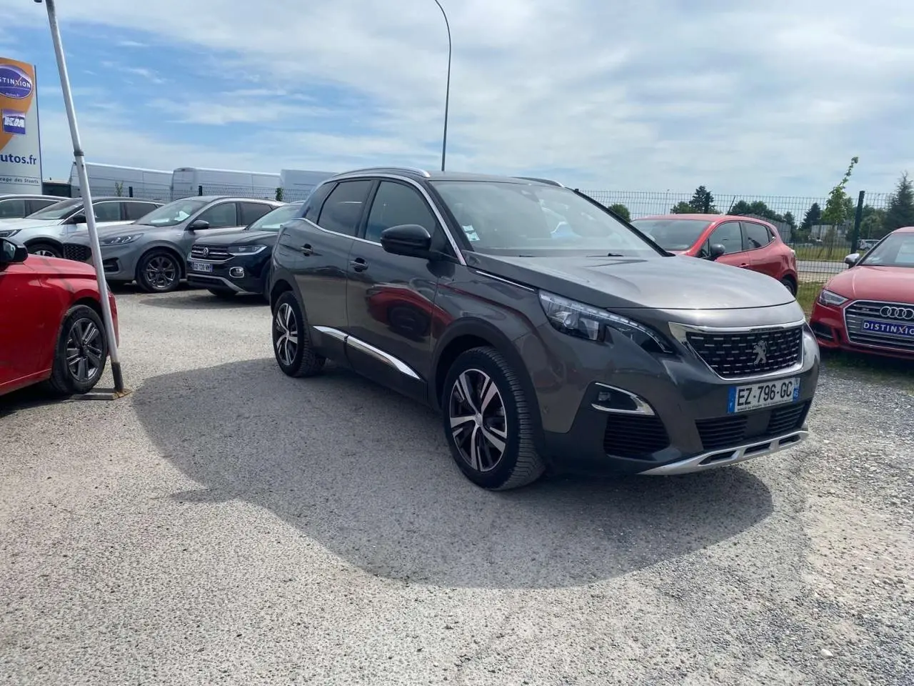 Peugeot 3008 gris platinium en 3/4 avant droit, avec barres de toit aluminium et projecteurs LED visibles.