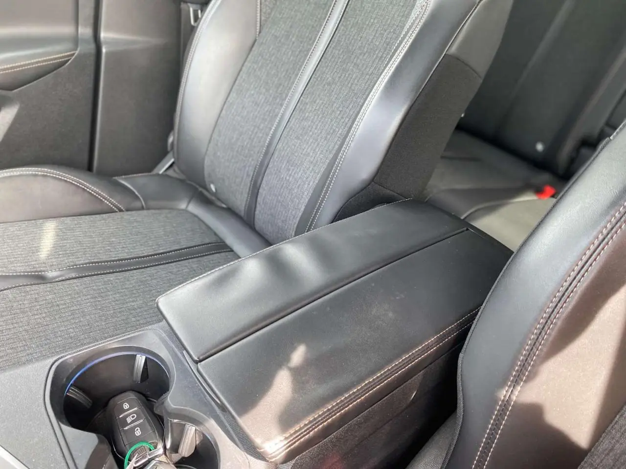 Gros plan sur l'accoudoir central noir et les sièges tissu et cuir du Peugeot 3008 GT Line 2018.