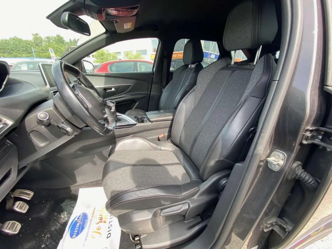 Vue intérieure côté conducteur du Peugeot 3008 gris platinium de 2018, sièges en tissu et cuir avec pédalier aluminium visible.