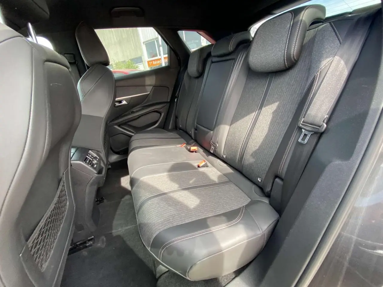 Vue intérieure du siège arrière droit du Peugeot 3008 gris platinium, montrant les finitions en tissu et cuir avec surpiqûres contrastées.