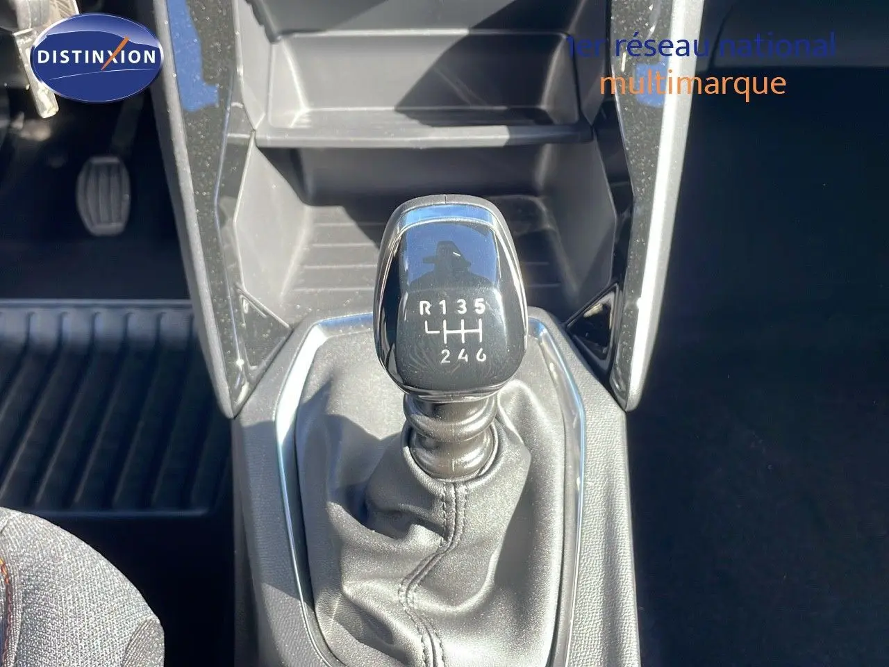 Le levier de vitesse manuel noir de la Peugeot 2008 blanc Okenite, vu en gros plan depuis l'intérieur.