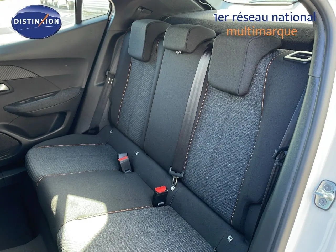 Vue intérieure arrière droite des sièges noirs avec surpiqûres orange du Peugeot 2008 blanc Okenite 2025.