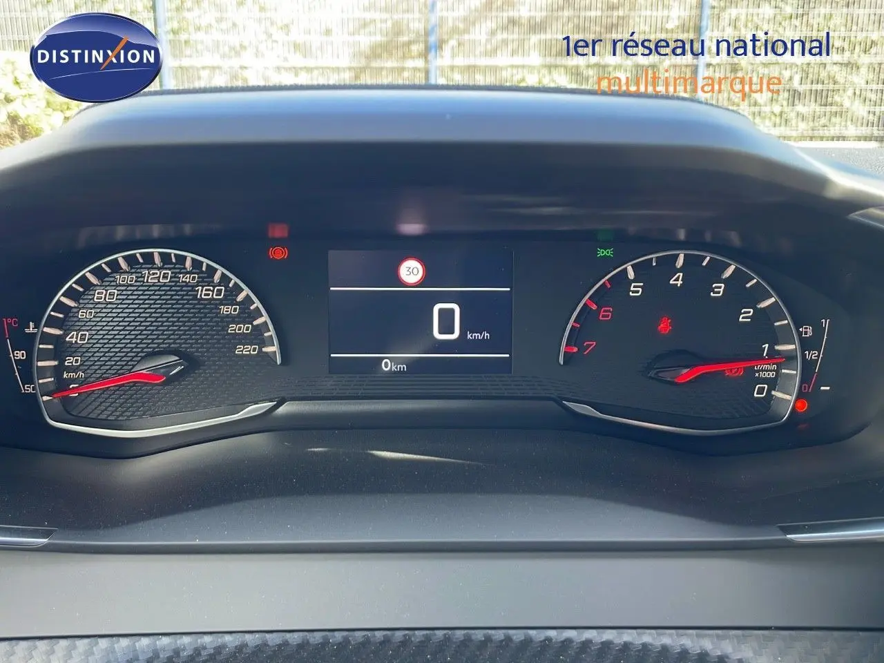 Tableau de bord numérique du Peugeot 2008 blanc Okenite, affichant vitesse zéro et compte-tours à l'arrêt.