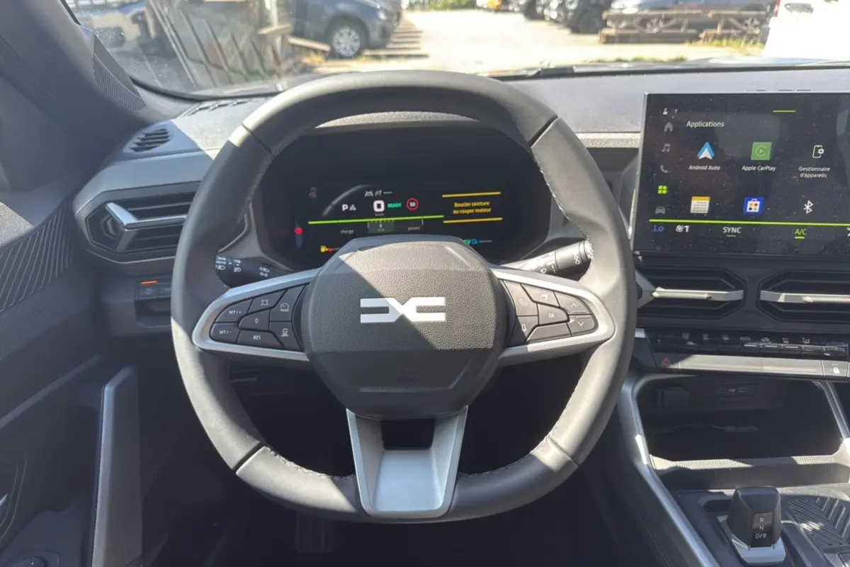 Vue intérieure centrée sur le volant cuir et le tableau de bord digital du Dacia Bigster gris schiste 2025.