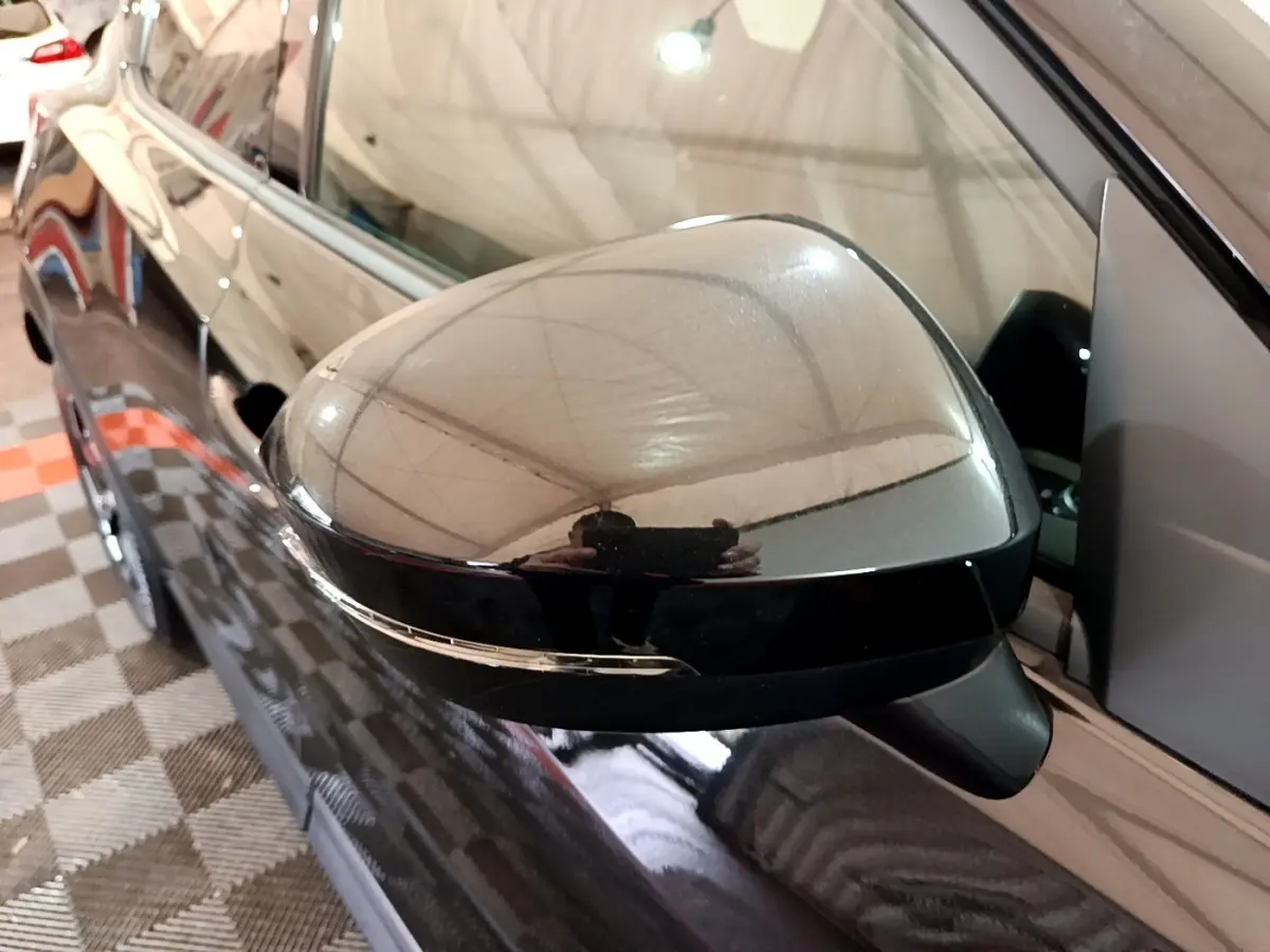 Rétroviseur côté gauche noir brillant d'un Nissan Juke Hybrid 143 Business+ 2022, vue rapprochée en intérieur.