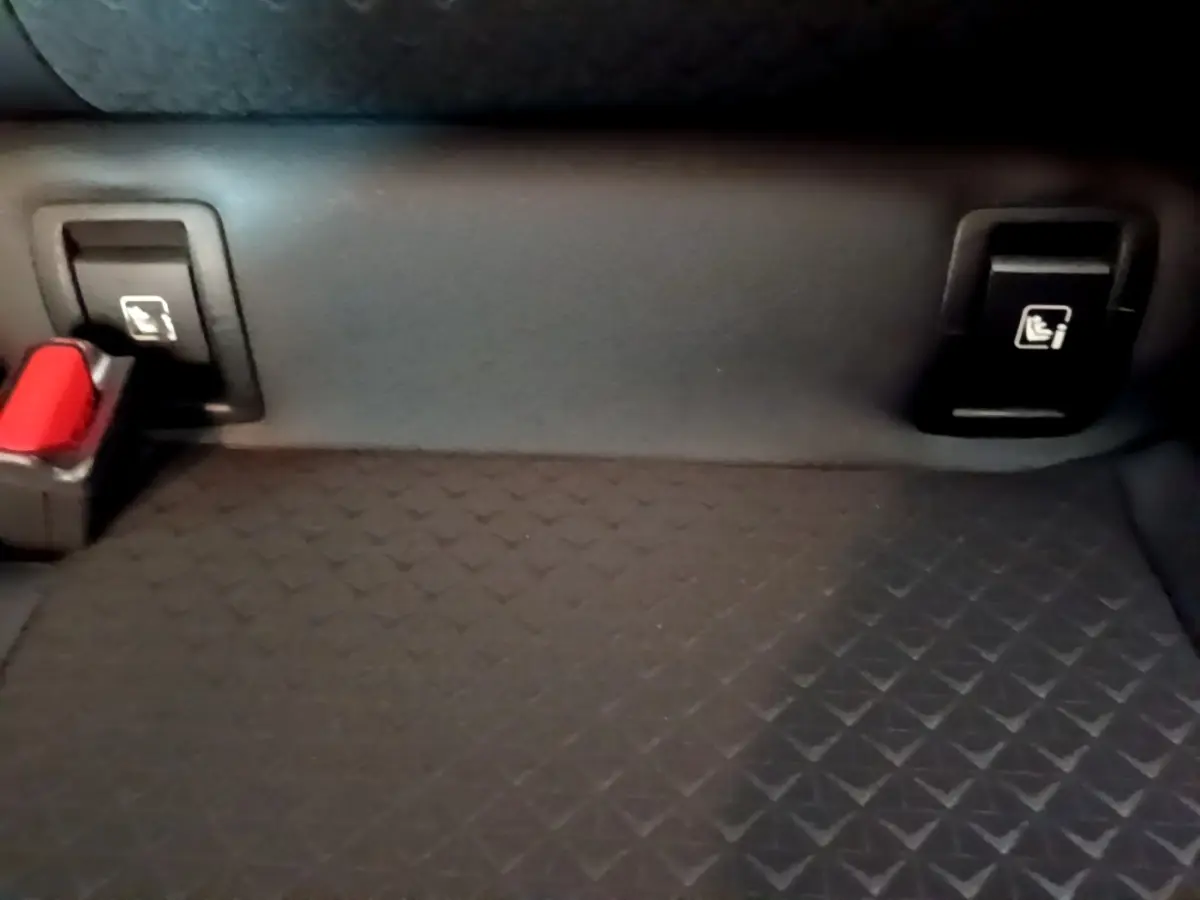 Détail de la banquette arrière noire du Nissan Juke Hybrid 2022 avec fixation Isofix et boucle de ceinture rouge.