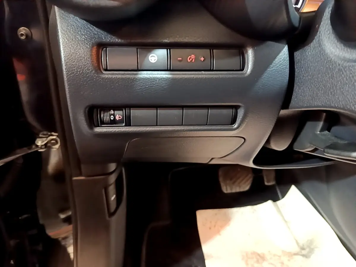 Vue intérieure côté conducteur du tableau de bord noir avec commandes d’éclairage et réglages du Nissan Juke Hybrid 2022.