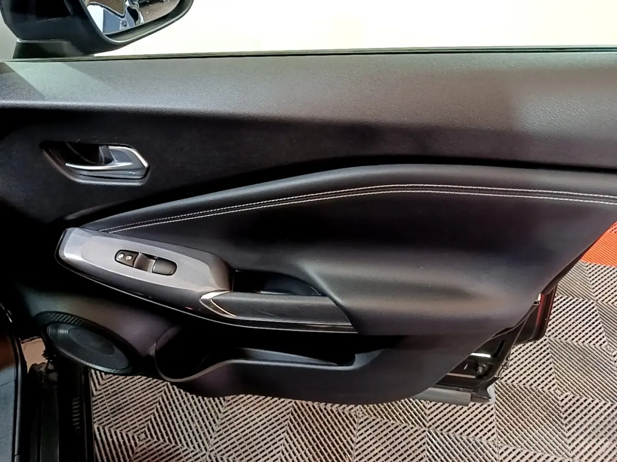 Vue intérieure du panneau de porte côté gauche noir avec commandes de vitres et poignée argentée du Nissan Juke Hybrid 2022.