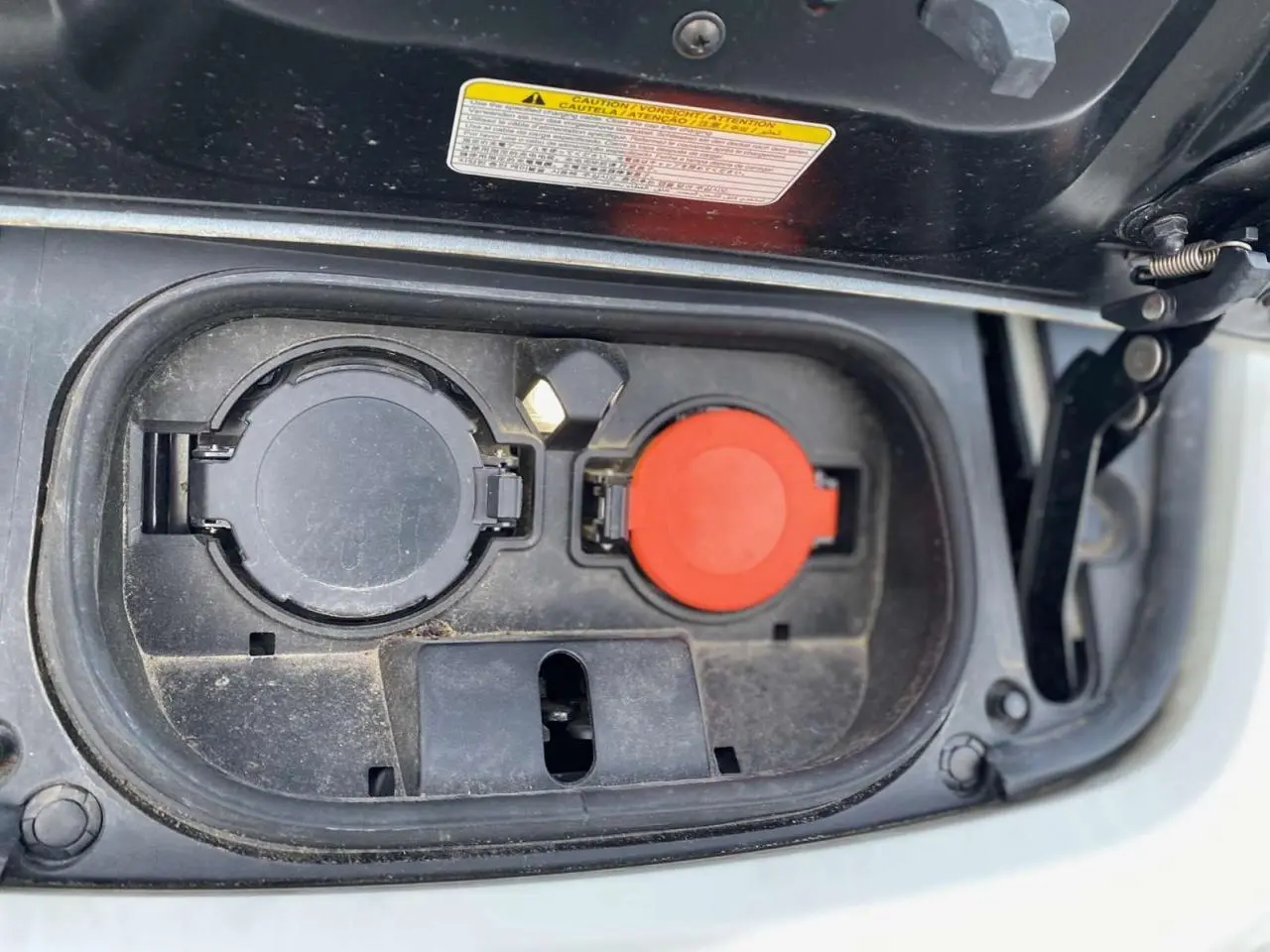 Gros plan sur la trappe de recharge électrique ouverte d'une Nissan Leaf 40 N-Connecta blanche, montrant les prises de charge.