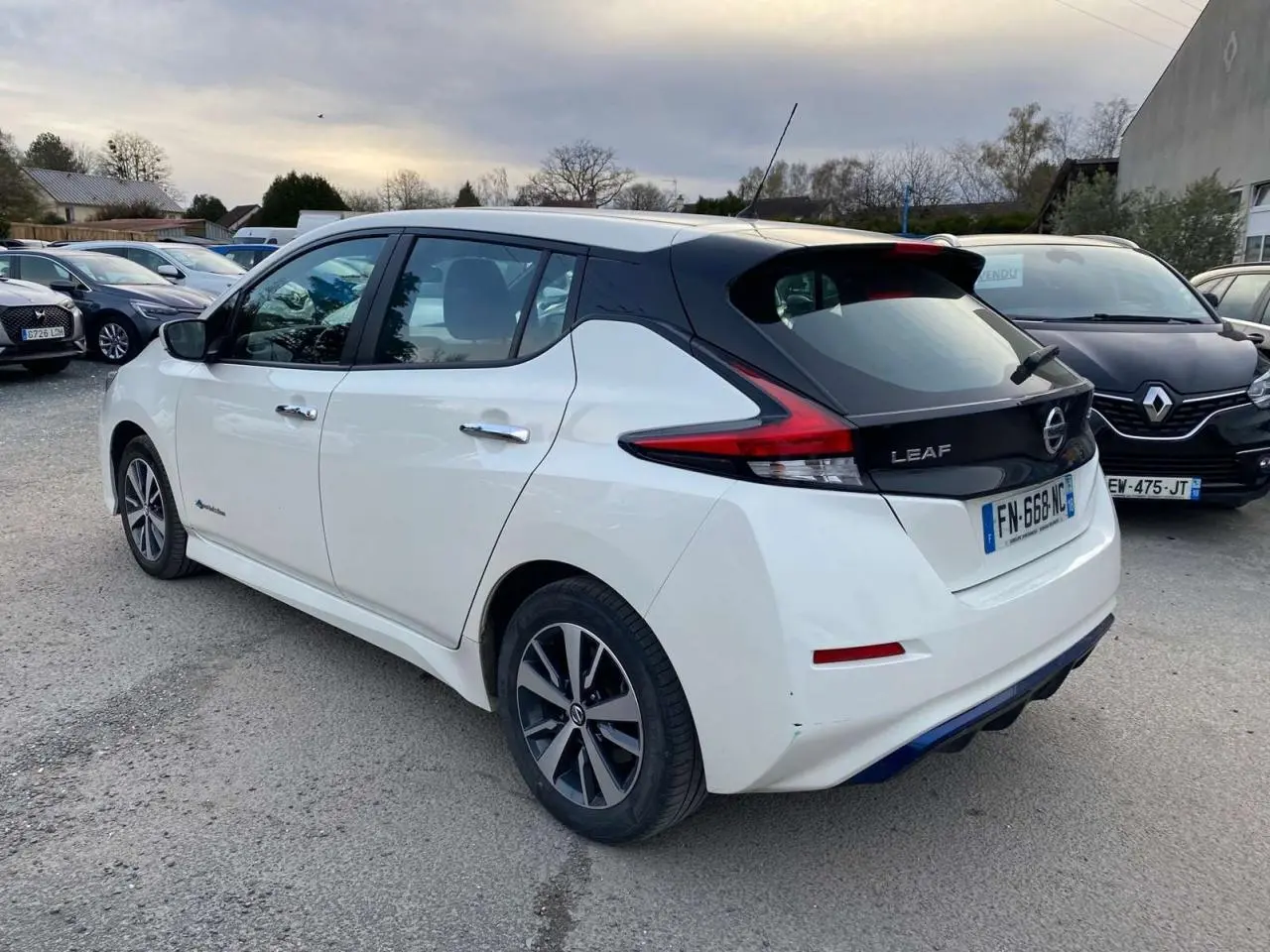 Vue 3/4 arrière droite d'une Nissan Leaf blanche 2020 avec feux arrière distinctifs et toit noir contrastant.