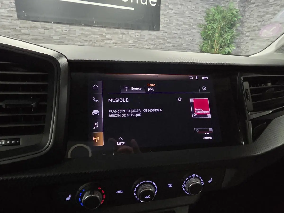 Tableau de bord de l'Audi A1 Sportback 2020 avec écran tactile MMI affichant la radio FM et commandes de climatisation.