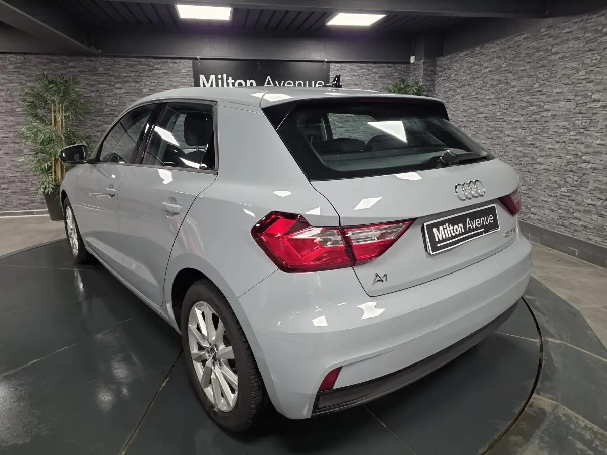 Vue 3/4 arrière droite d'une Audi A1 Sportback gris Manhattan avec jantes aluminium 16 pouces en showroom.