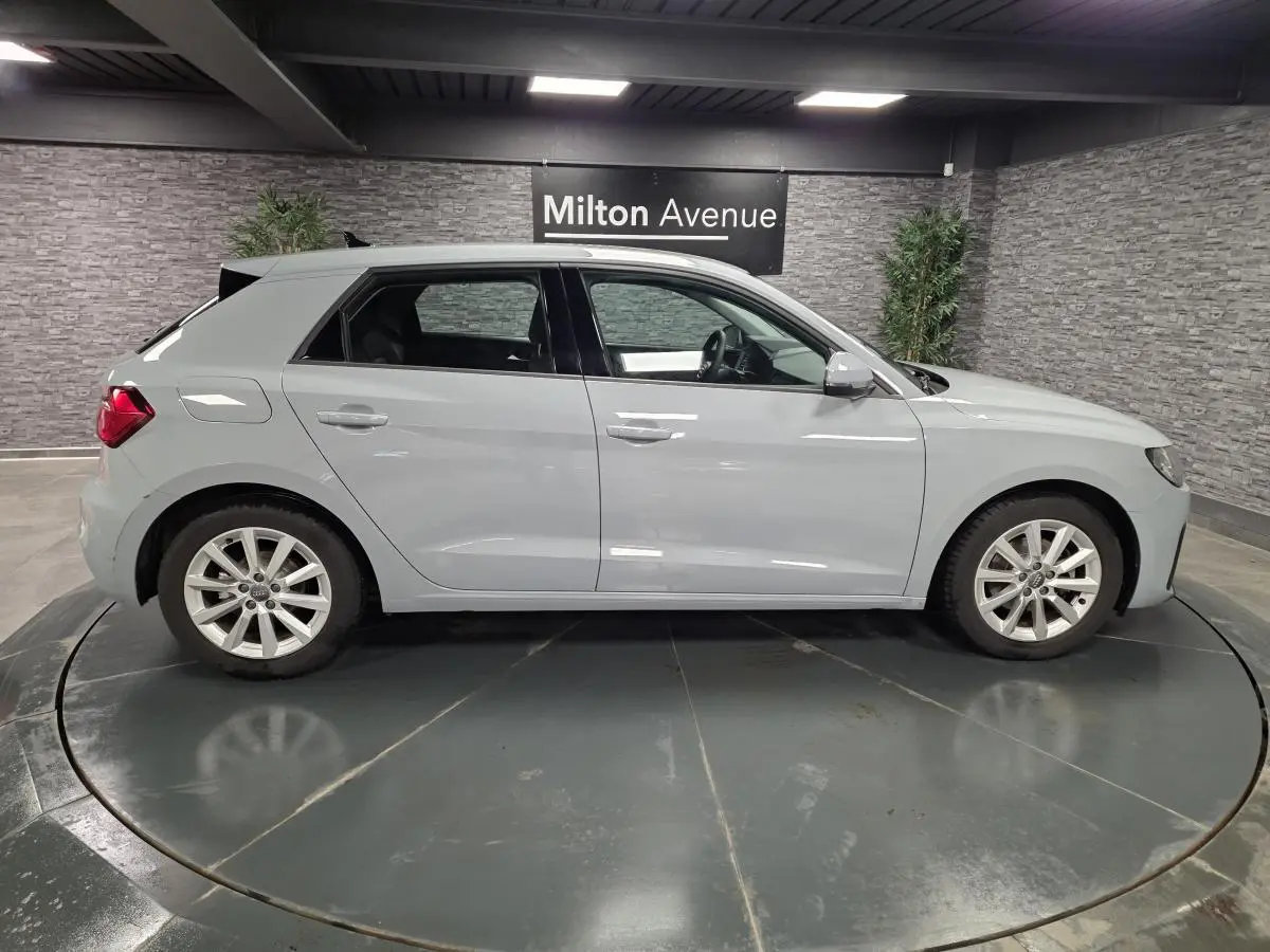 Profil côté droit d'une Audi A1 Sportback 2020 gris Manhattan avec jantes aluminium 16 pouces en intérieur showroom.