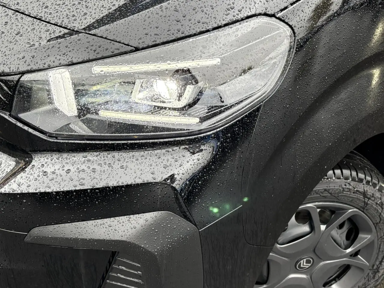Gros plan sur l'avant droit noir Perla du Citroën Jumpy 2025 avec phare Full LED et gouttes de pluie visibles.