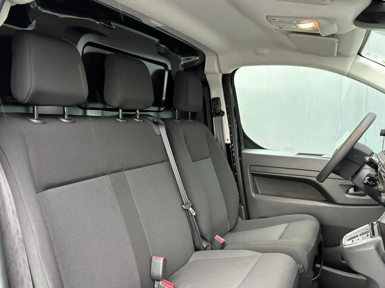 Intérieur du Citroën Jumpy 2025 vu côté droit, sièges tissu gris et tableau de bord fonctionnel noir.