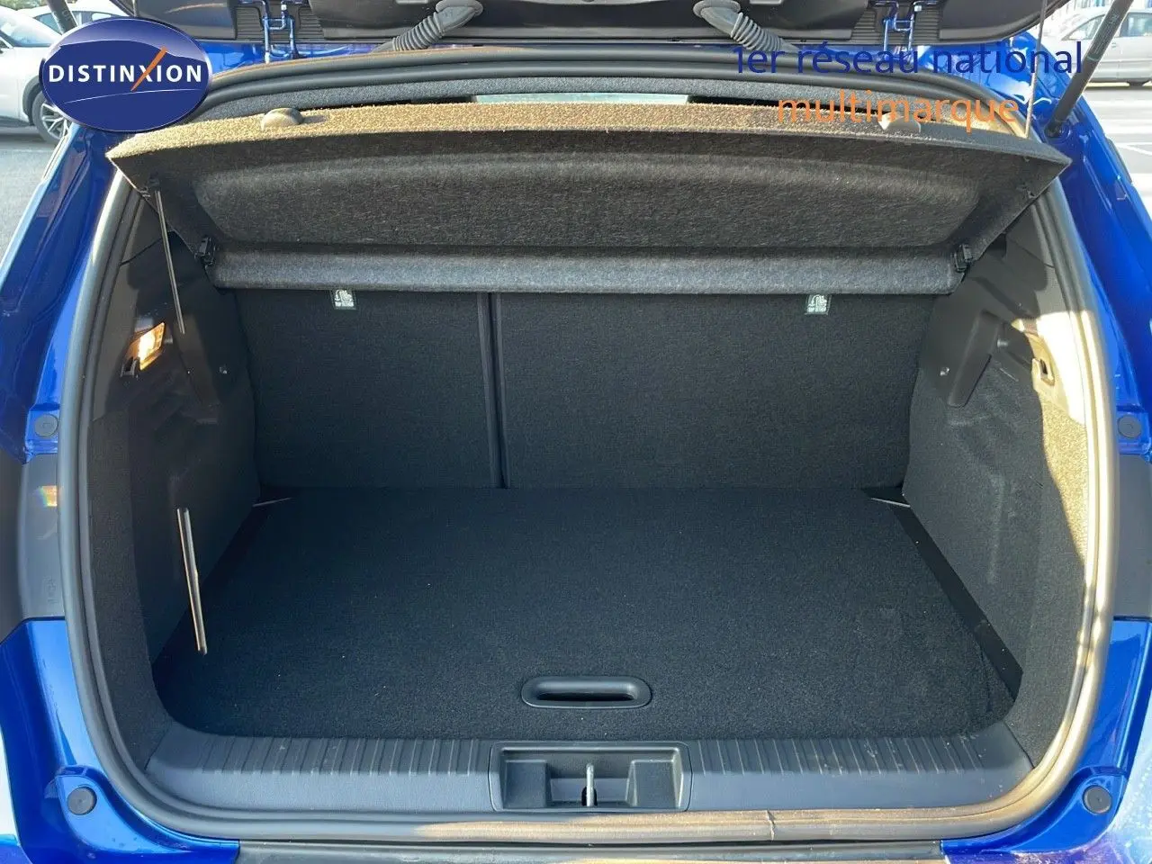 Coffre ouvert d'un Renault Captur E-Tech hybride 2025 bleu Iron Metal avec toit noir, vue arrière intérieure.
