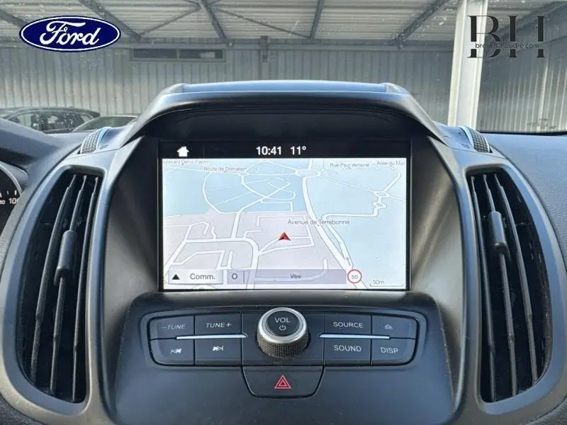 Vue rapprochée de l’écran GPS intégré au tableau de bord du Ford Kuga 2017, avec commandes audio visibles.