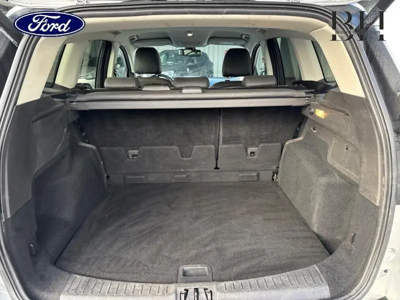 Coffre spacieux vu de l'arrière d'un Ford Kuga gris lunaire 2017 avec banquette rabattable et cache-bagages.