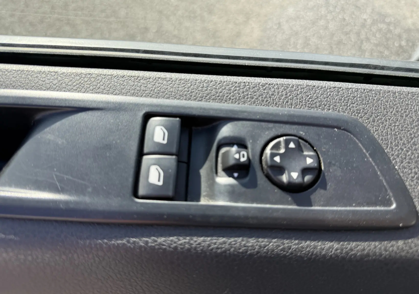 Gros plan sur les commandes de réglage des vitres et des rétroviseurs côté conducteur du FIAT Scudo cabine approfondie gris.
