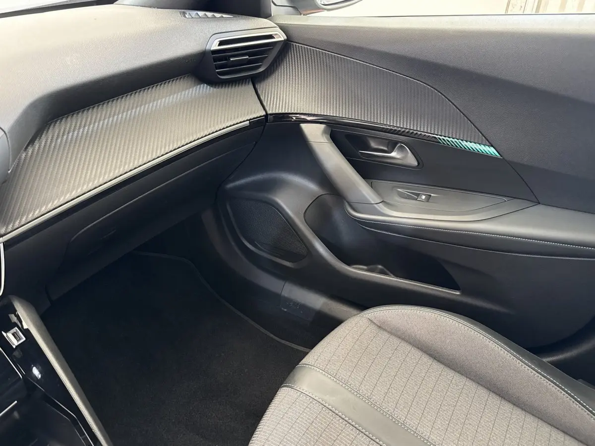 Intérieur côté passager du Peugeot 2008 gris clair, avec tableau de bord texturé et siège tissu gris.