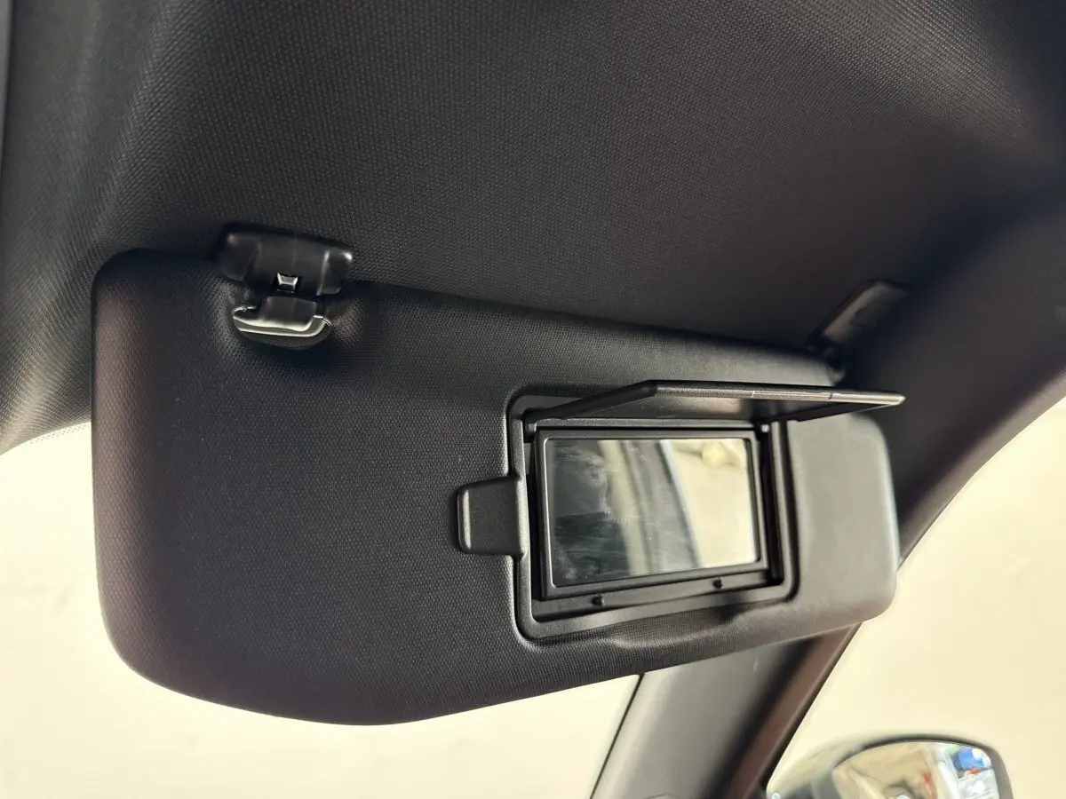 Miroir de courtoisie ouvert sur pare-soleil côté conducteur dans l’habitacle d’un Peugeot 2008 gris clair.