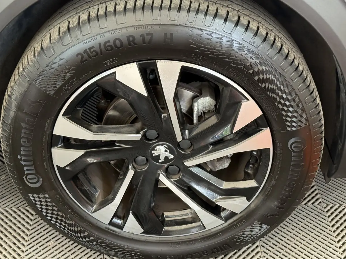 Gros plan sur la jante noire et argentée d’un Peugeot 2008 gris clair, mettant en valeur le logo lion central.