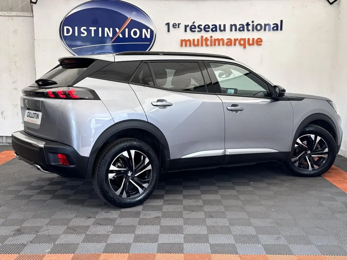 Vue profil droit d'un Peugeot 2008 gris clair 2023 avec toit noir et jantes alliage bicolores.
