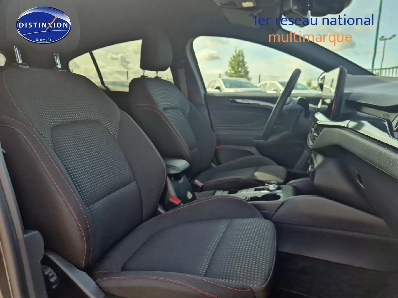 Intérieur avant de la Ford Focus 1.5 Ecoblue 115 ST-Line 2024, sièges noirs avec surpiqûres rouges et console centrale visible.