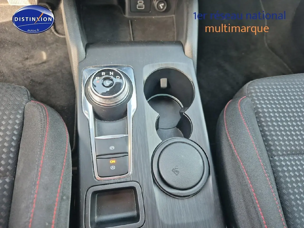 Vue rapprochée de la console centrale de la Ford Focus gris magnétique, avec sélecteur rotatif de boîte auto et porte-gobelets.