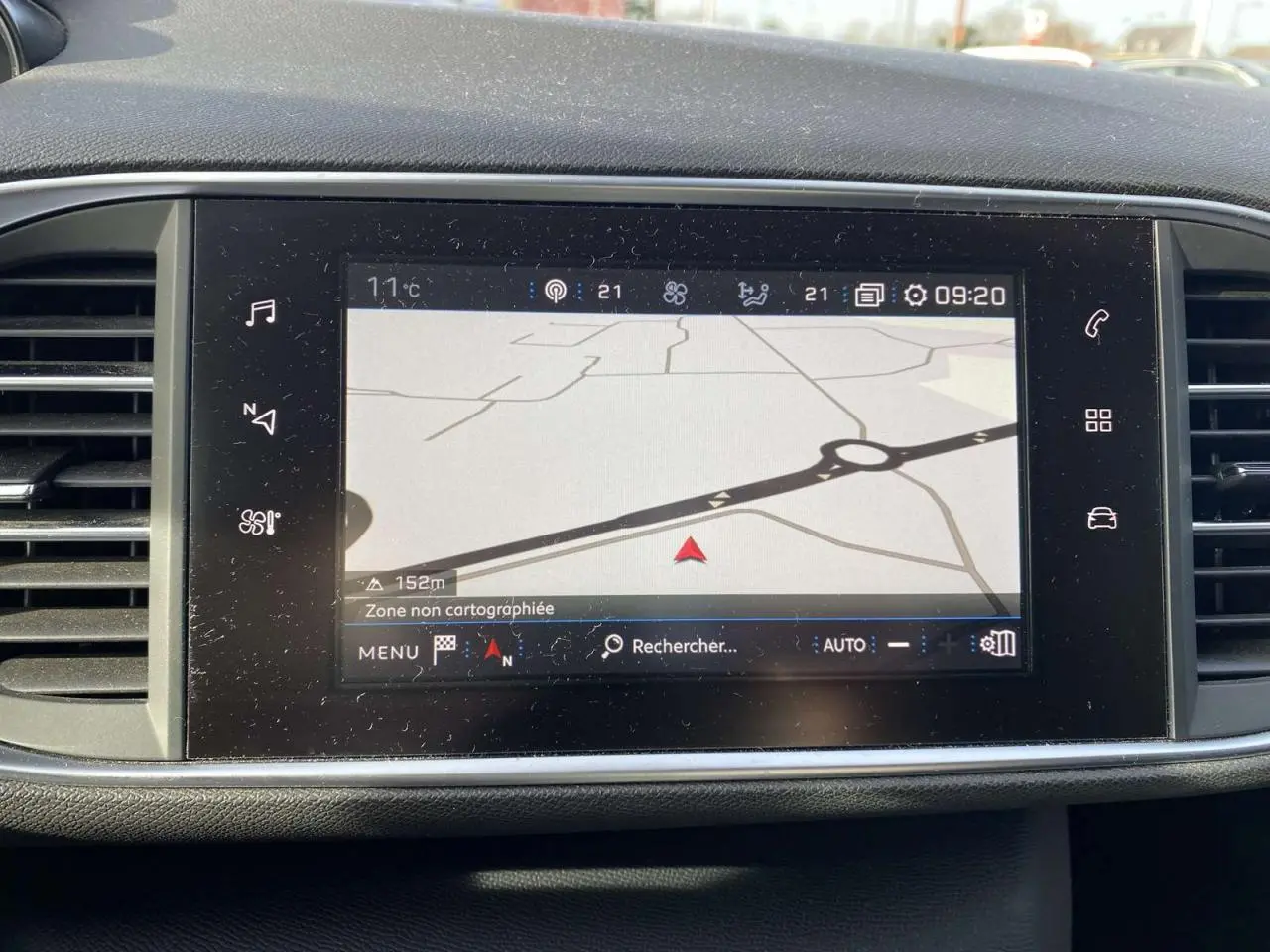 Écran tactile central du tableau de bord de la Peugeot 308 blanc nacré, affichant la navigation GPS en extérieur.