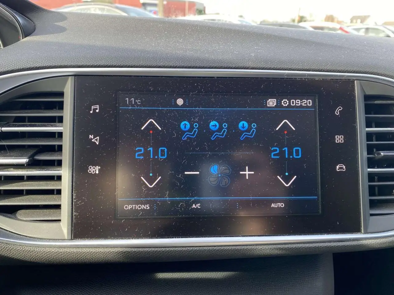 Écran tactile central de la Peugeot 308 blanc nacré de 2017 affichant la climatisation automatique bi-zone à 21°C.